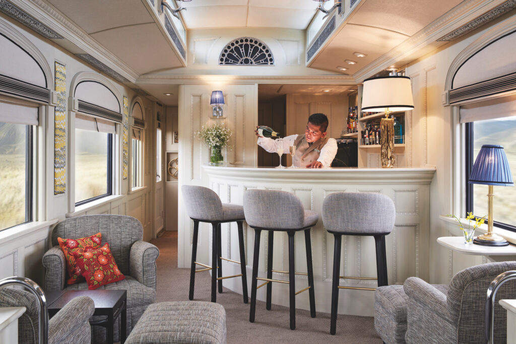 Bartender pouring a glass of champagne at the bar in The Andean Explorer train.