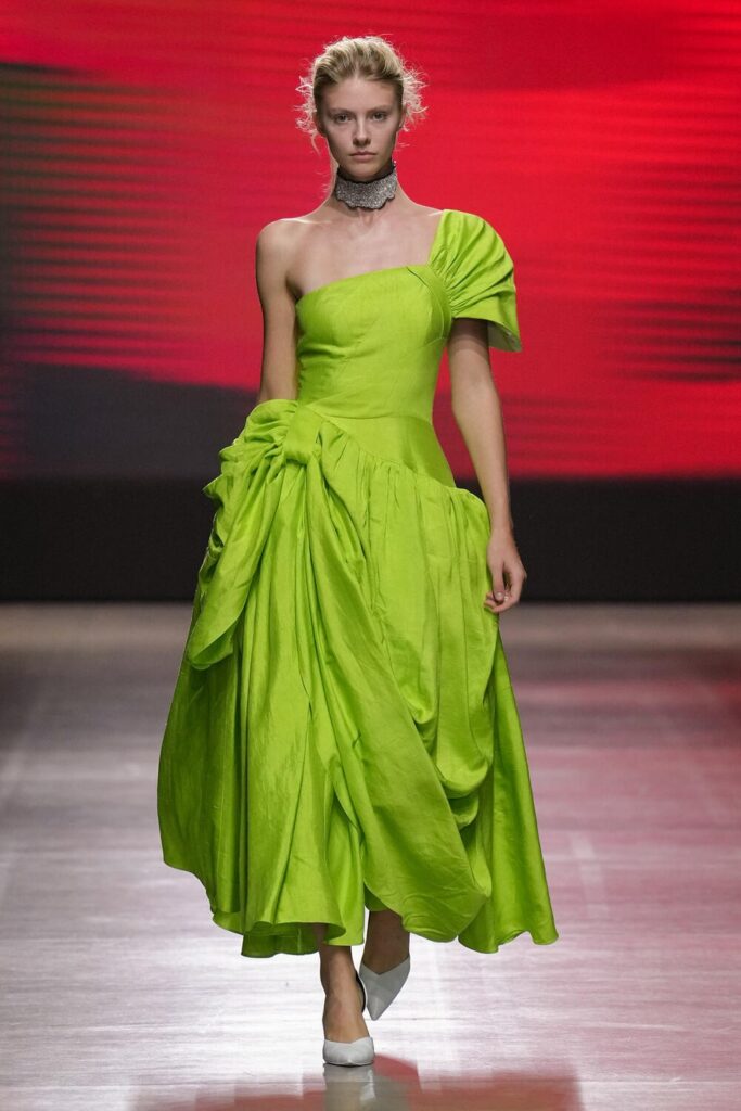 Female model walking down the runway in a neon yellow ruffled dress.